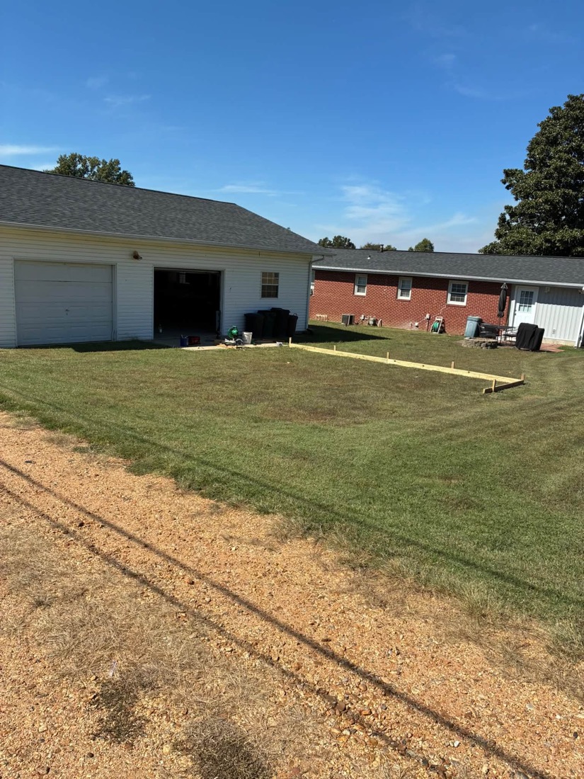 Marked-out project area beside a garage before gravel placement